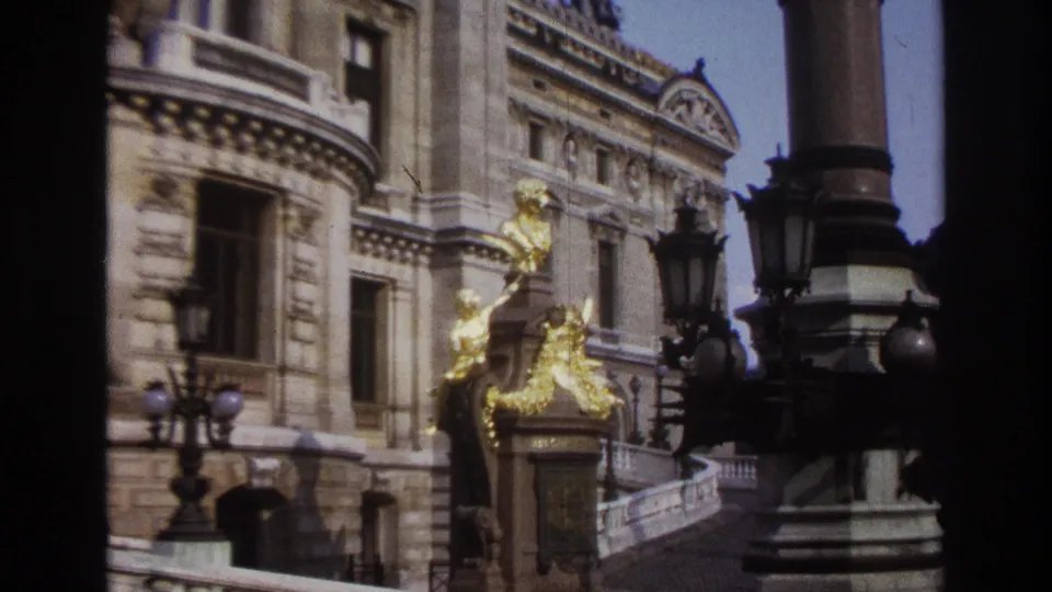 1967 Paris frame focusing on gilded figures and architectural details near the Moulin Rouge area, with lamps and steps visible.