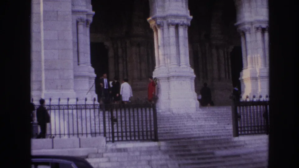 1967 Paris exterior with people near monumental stone arches, tall columns, broad steps, and black iron railings.