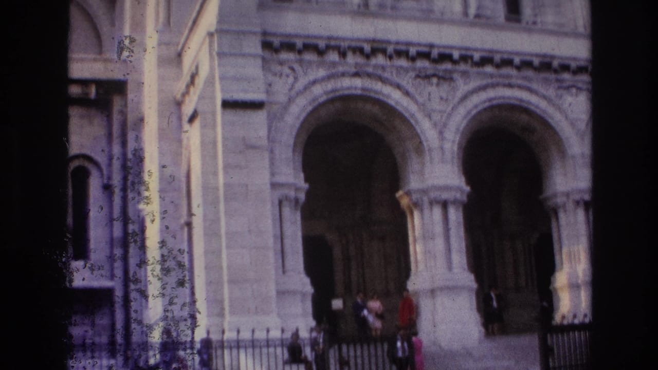 Close view of arched stone entrances, columns, steps, fencing, and visitors.
