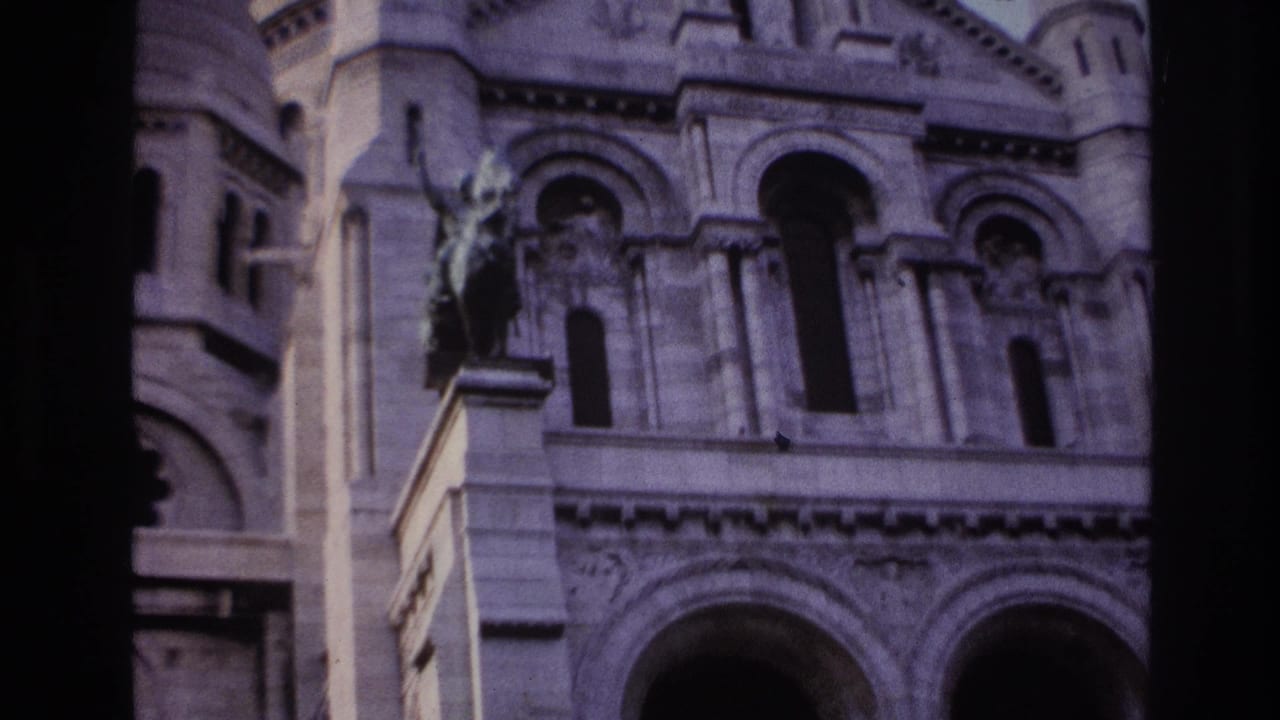 1967 Paris home-movie frame showing Sacre-Coeur stone arches, carved facade details, and shadowed openings.