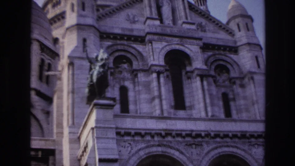 1967 Paris frame of Sacre-Coeur facade details, with arched openings and a dark vertical edge from the film scan.