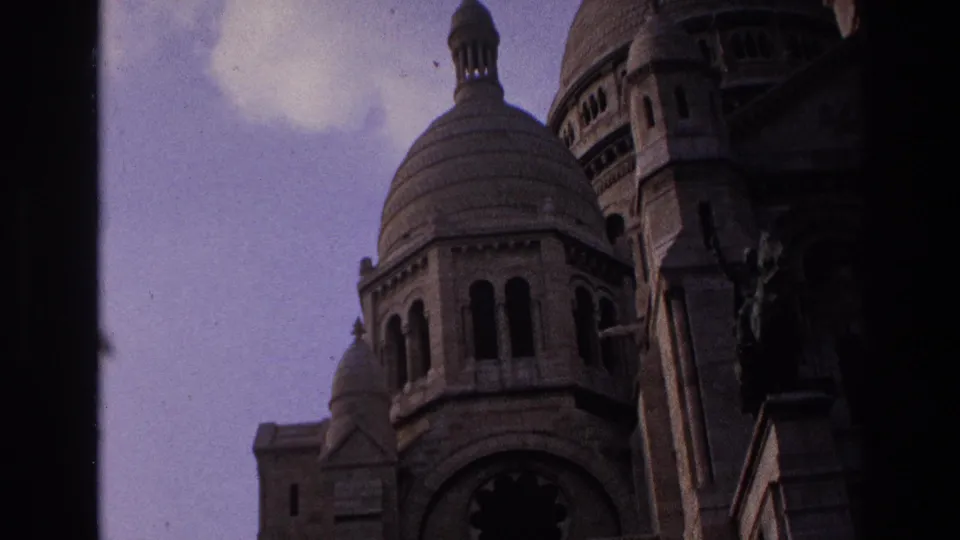 1967 Paris frame showing Sacre-Coeur dome, facade details, and a dark vertical frame line under a purple sky.