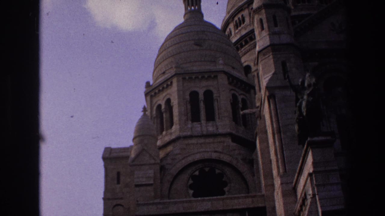 1967 Paris 8mm frame showing Sacre-Coeur's dome, arched openings, pale sky, and heavy dark vignette from the film frame.