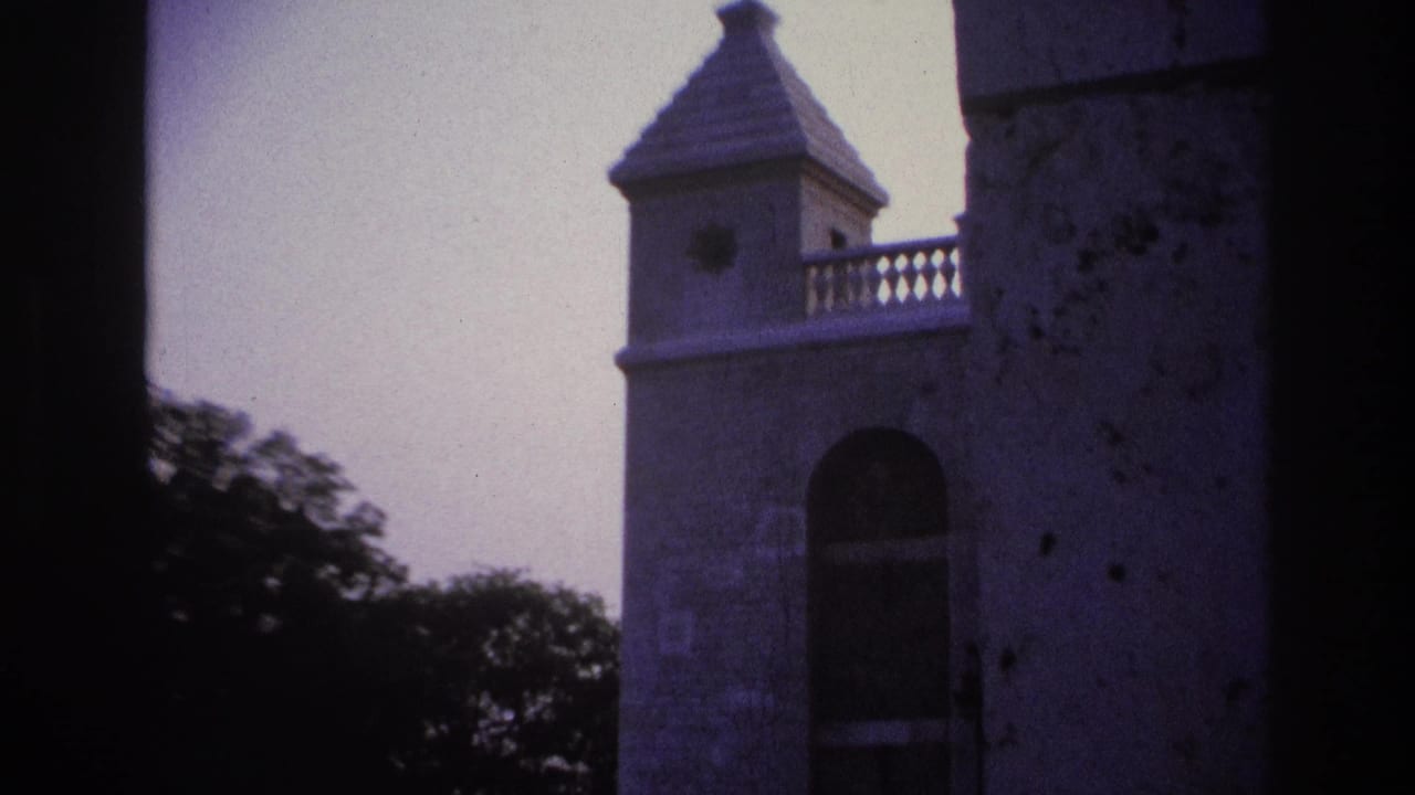 1967 Paris 8mm frame showing a pale stone tower, arched opening, conical roof, and trees through a dark architectural frame.