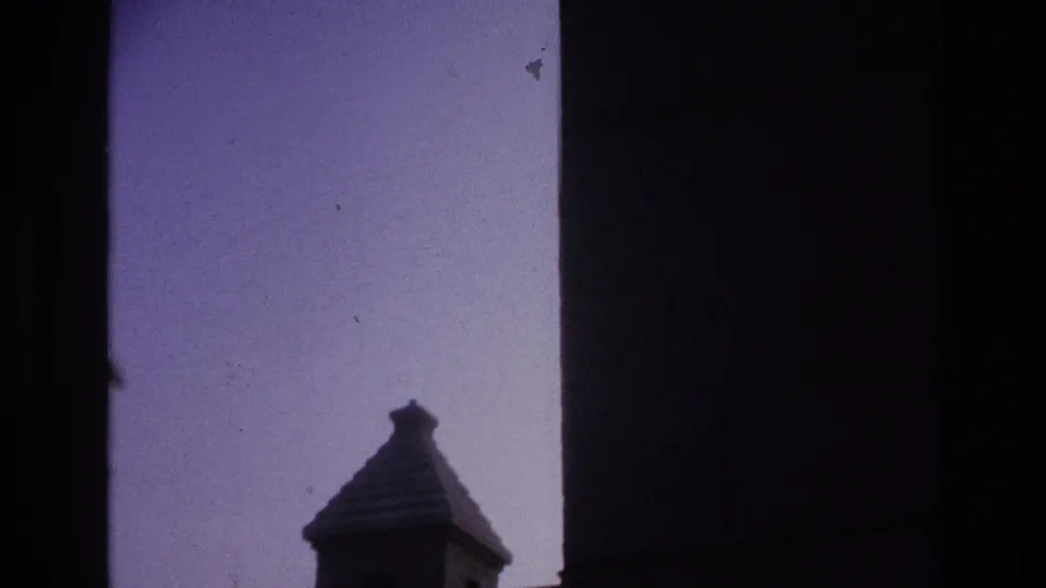 1967 Paris 8mm frame with the tower roof low in the composition, framed by dark vertical edges and a broad pale sky.