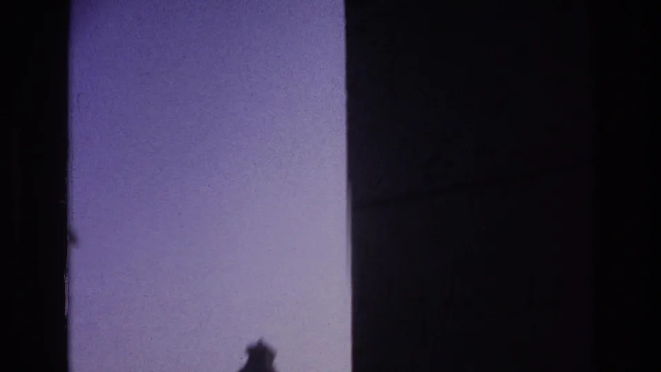 1967 Paris 8mm frame dominated by dark doorway framing and pale sky, with a small blurred portion of the tower roof near the lower edge.