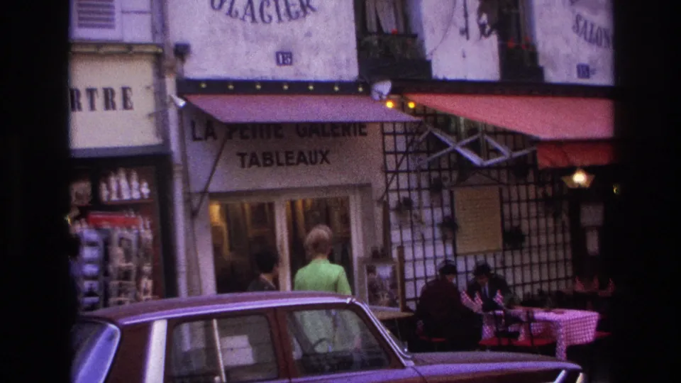 1967 Paris street scene with a woman in a lime green coat near outdoor tables, diners under red awnings, and a maroon car in the foreground.