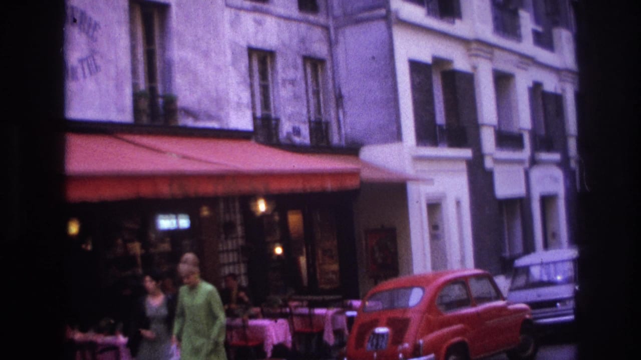 1967 Paris street view showing a patisserie frontage, red awning, pedestrians, cafe tables, and a red Citroen 2CV at the curb.