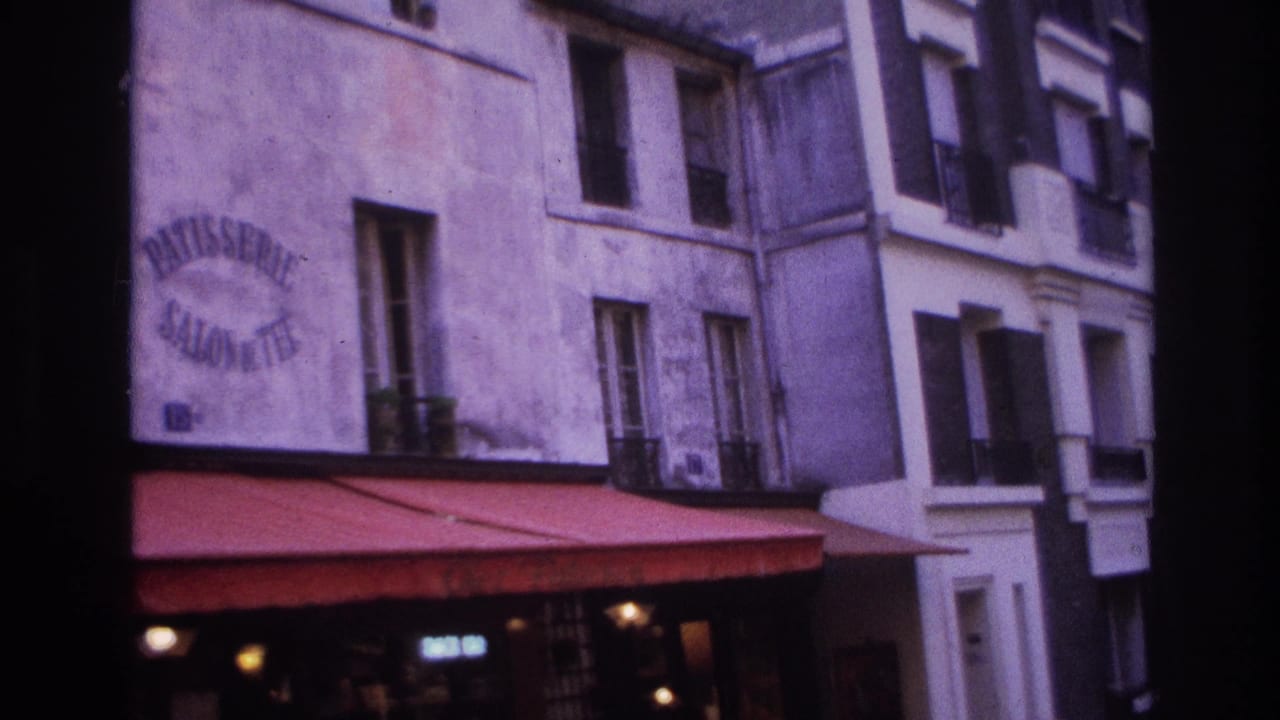 Upper bakery facade with painted Patisserie Salon de The sign above a red awning and apartment windows.