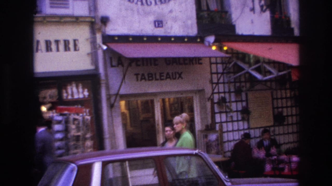 1967 Paris street view with cafe awnings, storefront lettering, pedestrians near the sidewalk, and a car in the foreground.