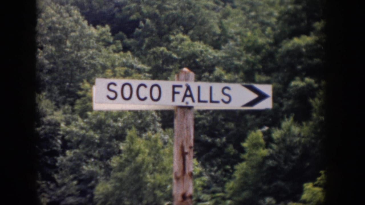 Wooden SOCO FALLS arrow sign standing in front of dense green trees.