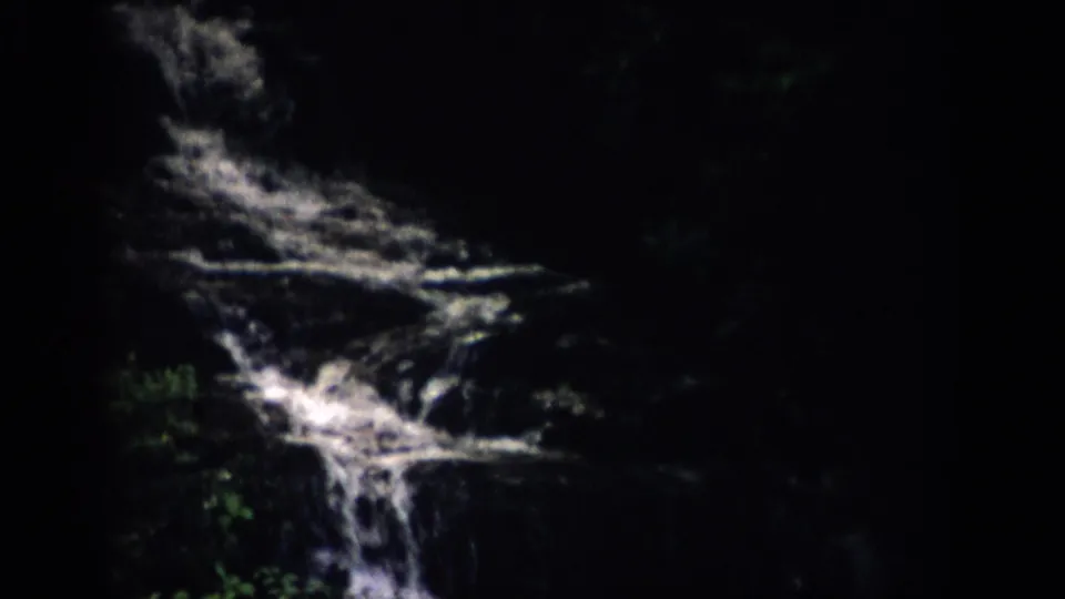 1959 Colorado 8mm frame showing white water cascading over dark, wet rock ledges with foliage at the edge.