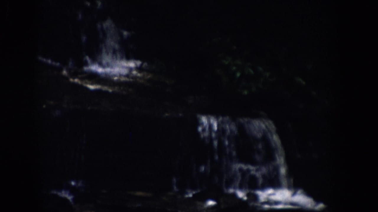 Tiered stream with small waterfalls crossing dark rock shelves.