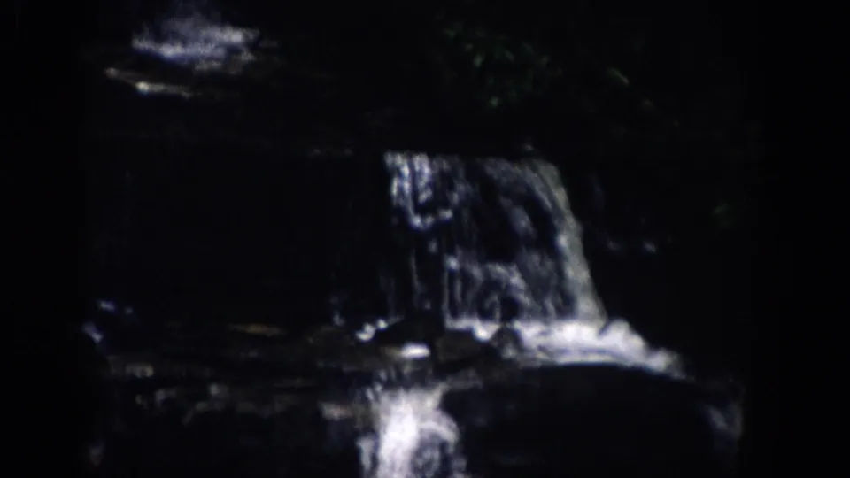 1959 Colorado 8mm still of water pouring from a flat rock ledge into a shadowed pool below.