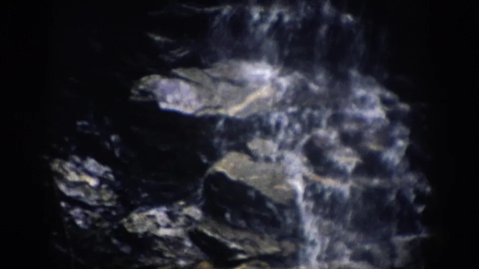 1959 Colorado 8mm frame of water sliding and foaming across dark, sharp-edged rock ledges.