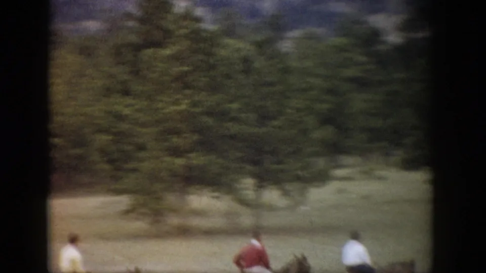Horseback riders in a Colorado mountain setting, framed by trees, open grass, and dark 8mm film borders.