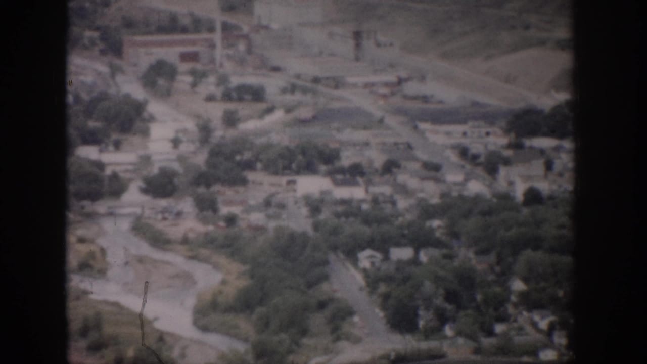 1959 Colorado 8mm aerial view showing roads, trees, open land, and scattered structures across a valley.