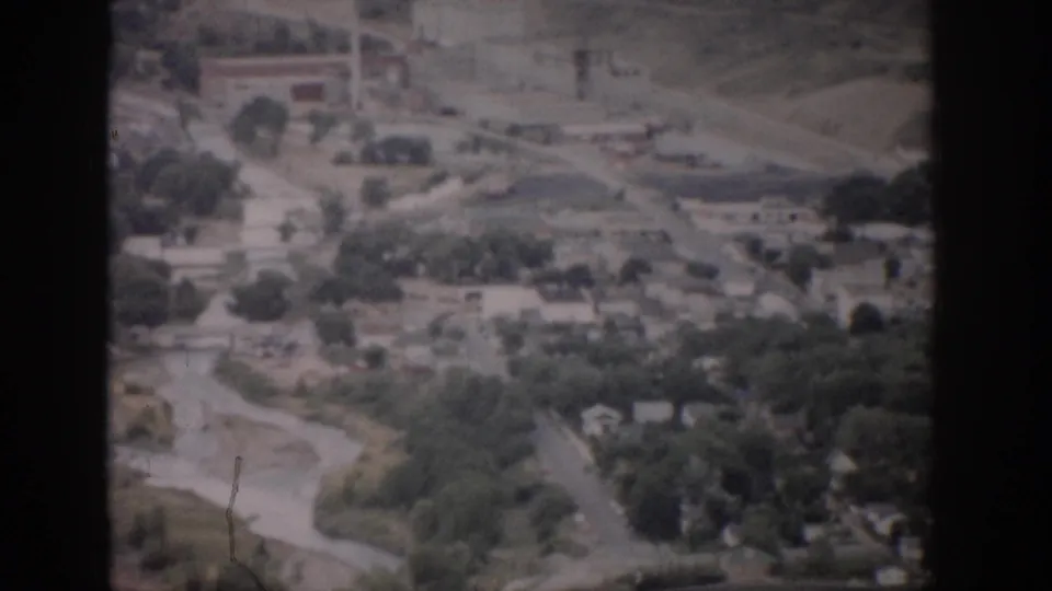 1959 Colorado 8mm aerial view showing roads, trees, open land, and scattered structures across a valley.