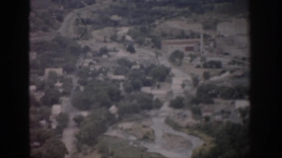 1959 Colorado aerial view with houses, roads, trees, open lots, and a pale winding river or creek channel.