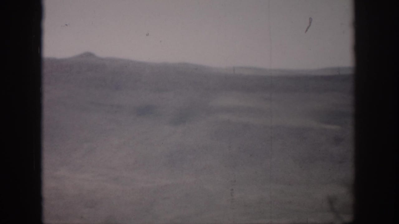 Open hazy hills and valley floor framed by dark vertical bands.