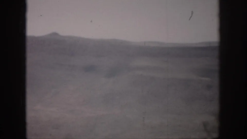1959 Colorado 8mm frame with soft, hazy hills and open valley terrain seen through dark vertical framing.