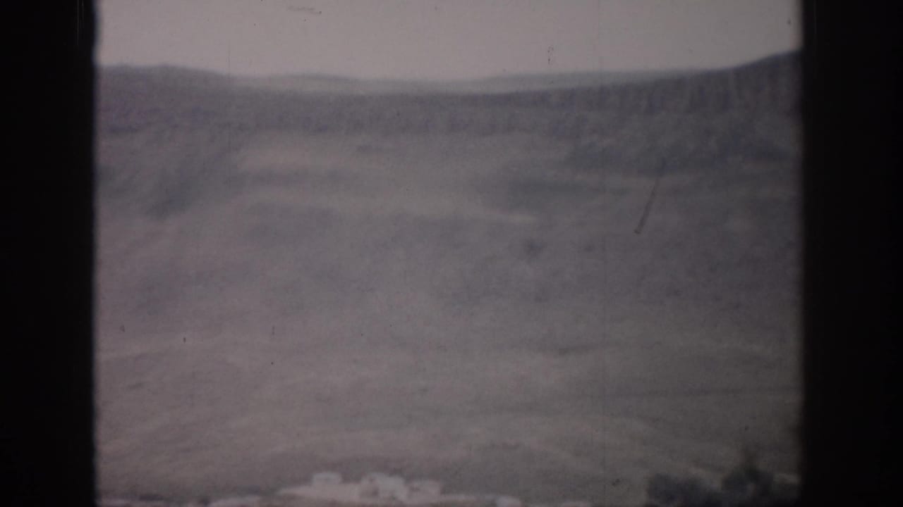 Distant hills and open valley seen through dark window framing.