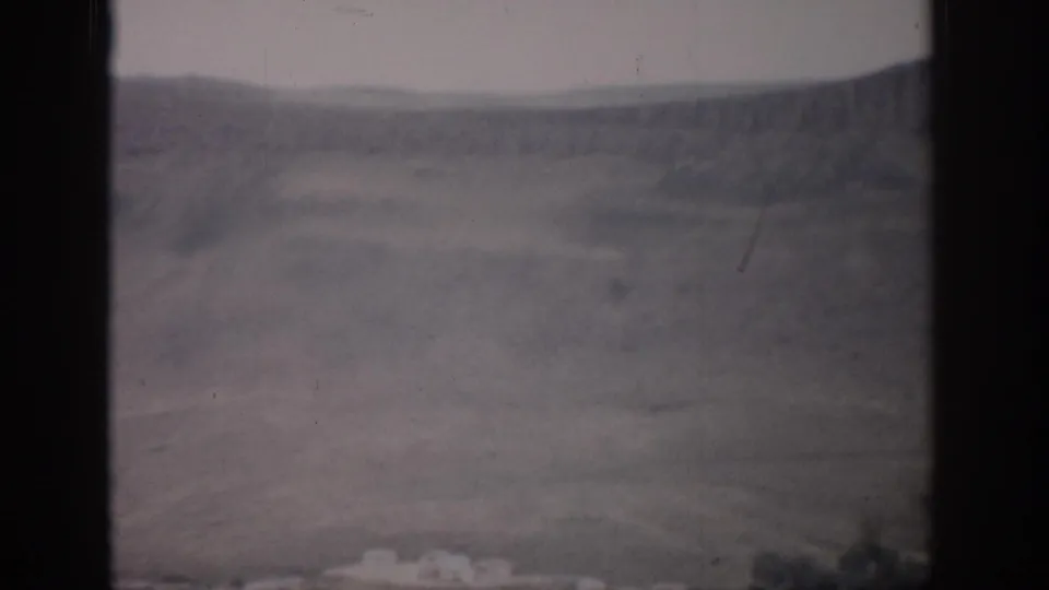 1959 Colorado home-movie frame showing an open valley and distant rolling hills through dark window edges.