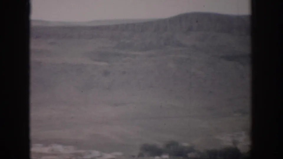 A soft 8mm view of a broad Colorado valley with rolling hills, sparse vegetation, and dark window borders.