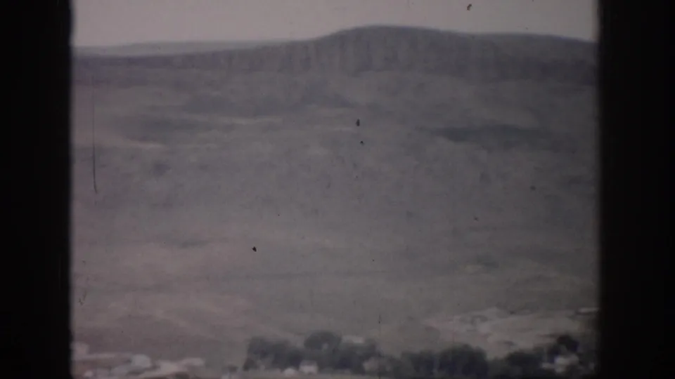 Colorado valley landscape from 1959 home-movie footage, showing distant hills, open fields, and dark window edges.