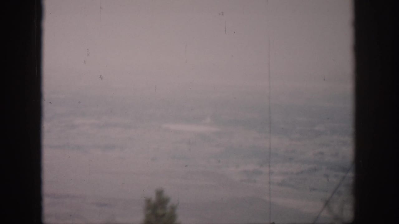 Hazy distant landscape viewed through dark vertical window mullions.