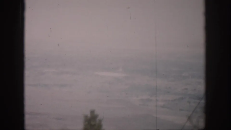 1959 Colorado 8mm view of a hazy landscape beyond dark window mullions, with soft sky and muted terrain.