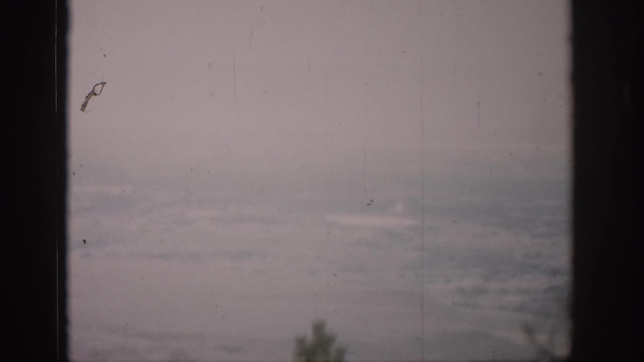 Hazy Colorado landscape viewed through dark window mullions in 1959 8mm home-movie footage.