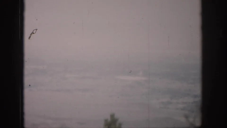 Hazy Colorado landscape viewed through dark window mullions in 1959 8mm home-movie footage.