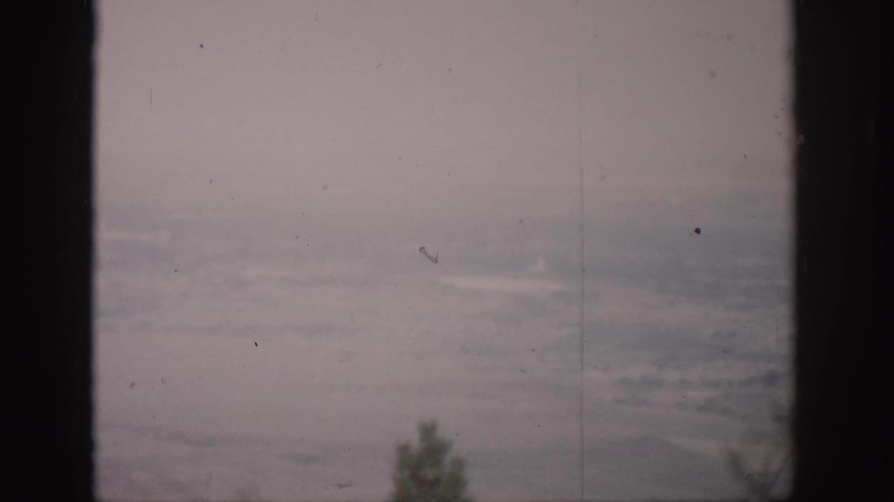 Blurred distant terrain behind a central dark window mullion.