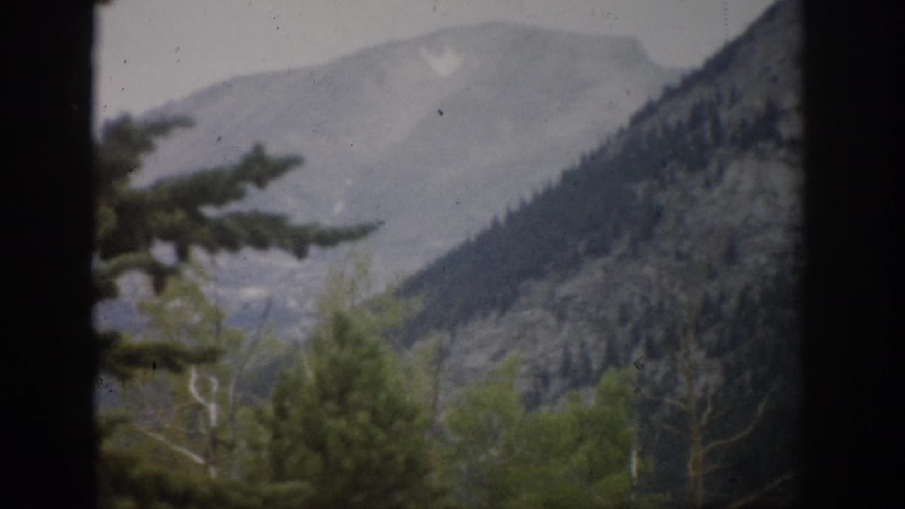 Mountain valley view with trees in the foreground and distant ridges.