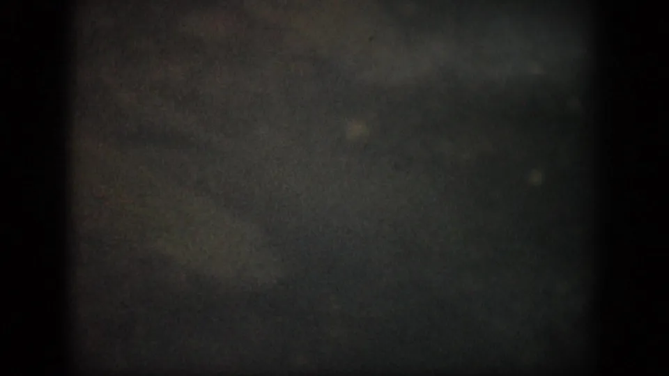 1959 Colorado 8mm frame showing murky shallow water through dark film edges, with faint underwater forms and visible grain.