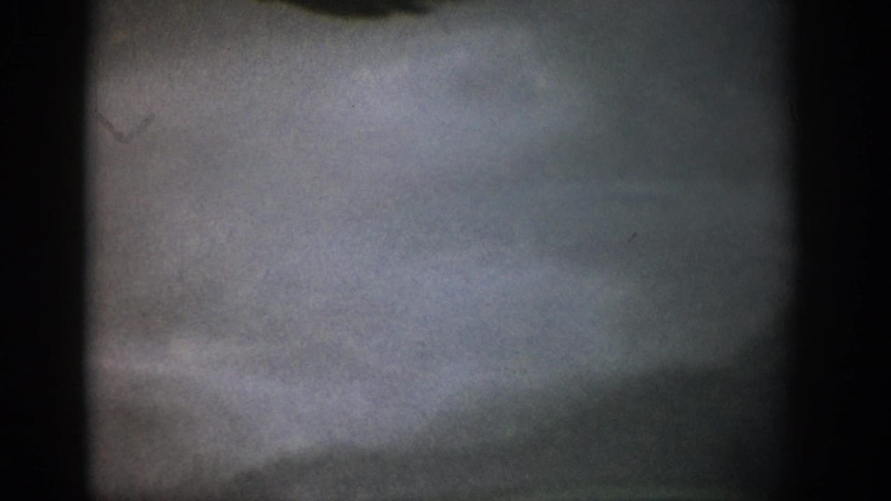 1959 Colorado 8mm frame showing a hazy underwater streambed, muted gravel tones, and heavy dark frame edges.