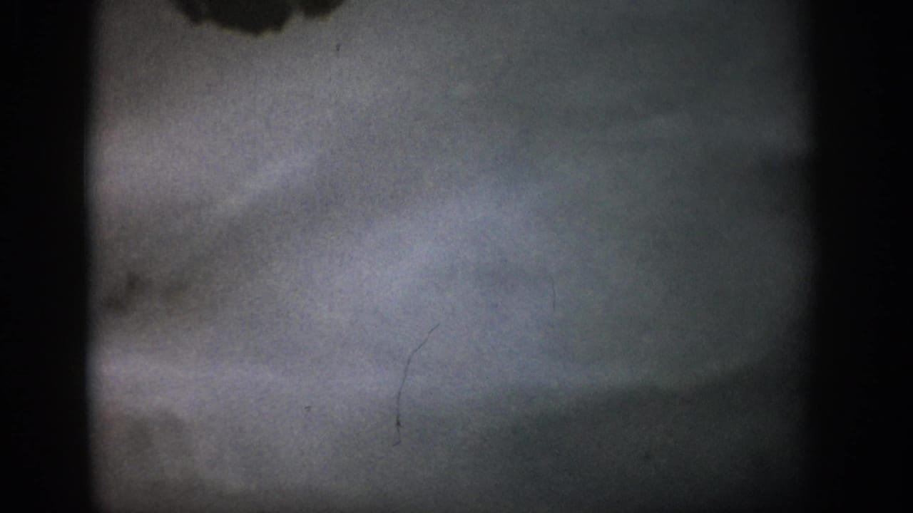 1959 Colorado 8mm frame with a blurred underwater streambed, pale water haze, film grain, and dark gate edges.