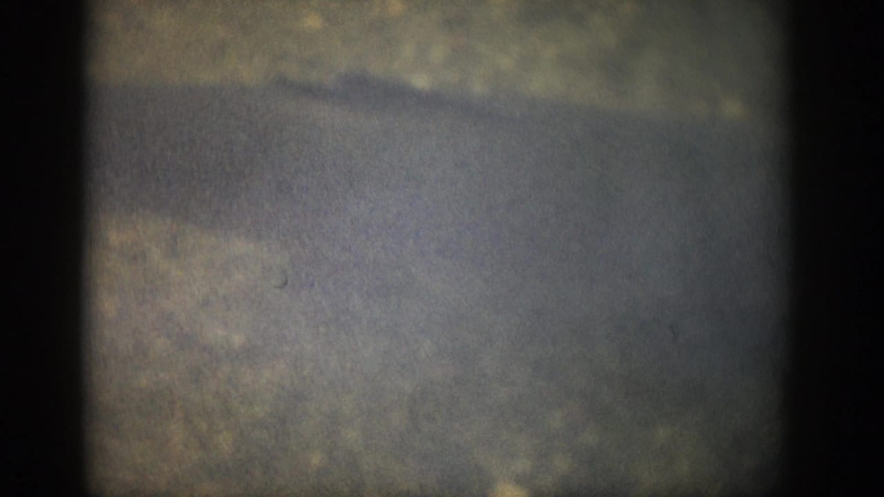 1959 Colorado 8mm frame with cloudy shallow water, subtle ripples, faded color, and visible film-frame darkness at the sides.
