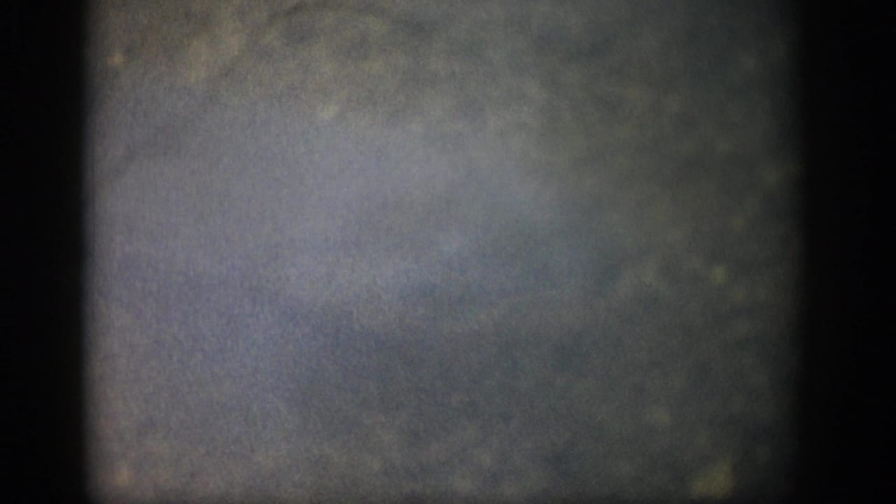 1959 Colorado 8mm frame showing a dim underwater scene, lighter haze near center, and dark edge artifacts from the film scan.