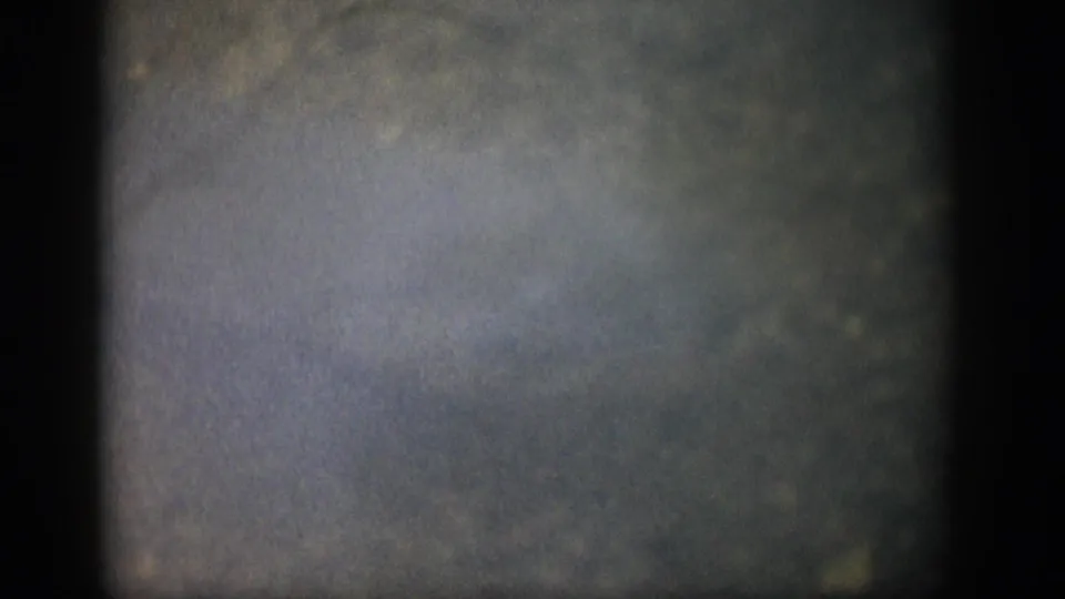 1959 Colorado 8mm frame showing a dim underwater scene, lighter haze near center, and dark edge artifacts from the film scan.