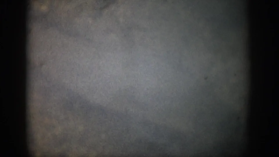 1959 Colorado 8mm frame with murky underwater blue-gray tones, dark borders, grain, and indistinct mottled forms.