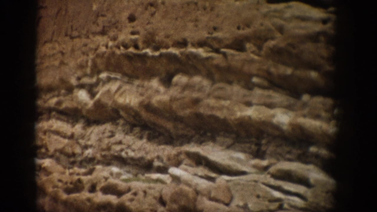 1959 Colorado 8mm frame showing a close-up of stratified sandstone, rough ledges, and warm earth-toned rock texture.