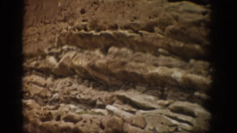 1959 Colorado 8mm frame showing a close-up of stratified sandstone, rough ledges, and warm earth-toned rock texture.