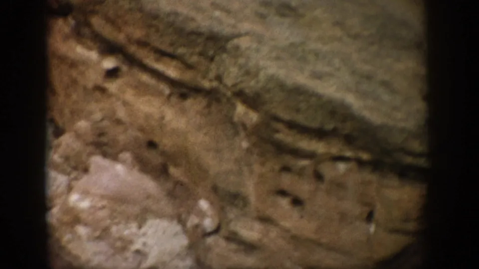 1959 Colorado 8mm frame showing a closer sandstone ledge with pitted texture, soft focus, and warm natural light.