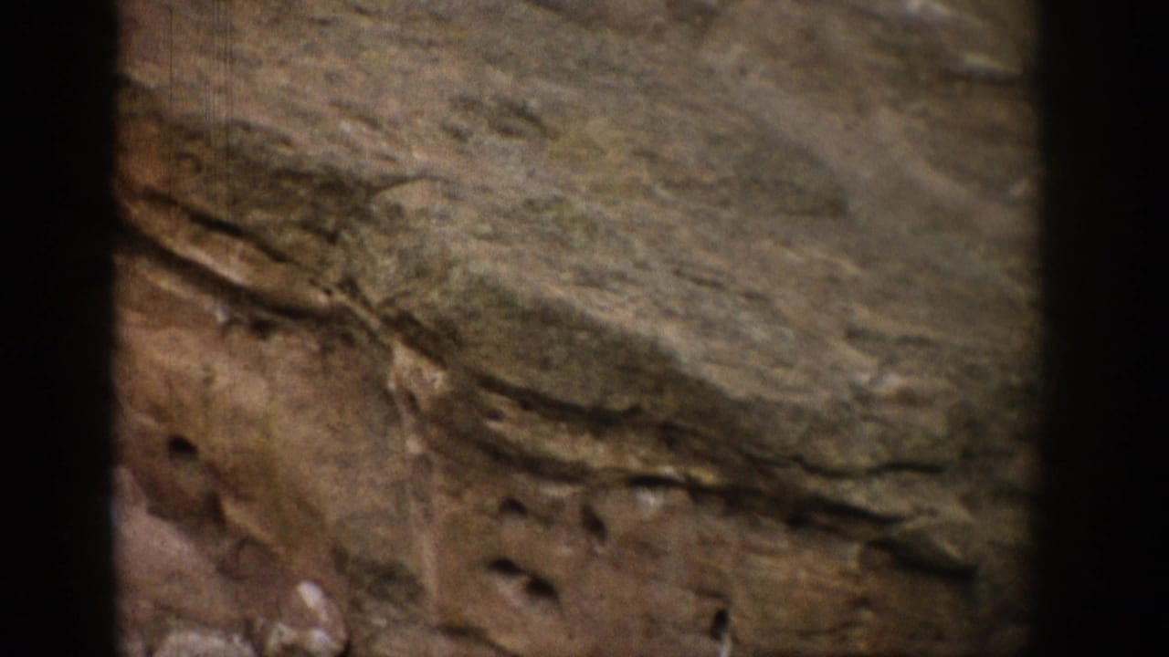 1959 Colorado 8mm frame showing a close view of layered, weathered rock on a mountainside.