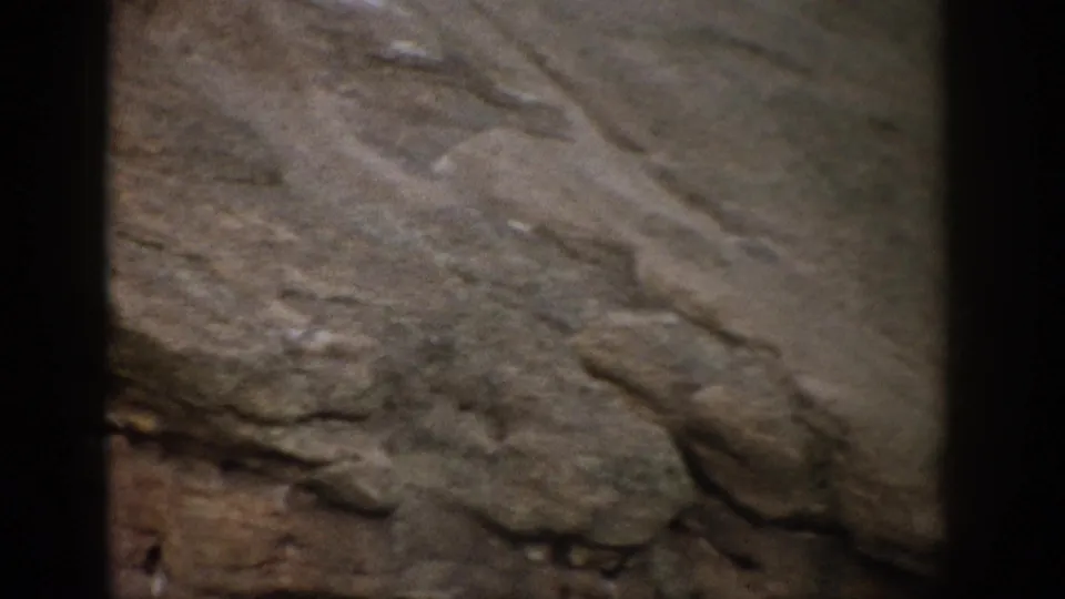 1959 Colorado 8mm frame showing muted green-gray and brown rock textures near the end of the pan.