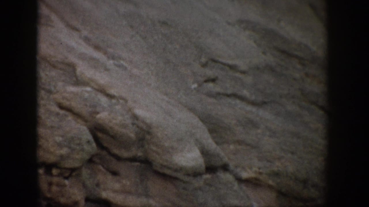 1959 Colorado 8mm frame showing a rocky hillside surface with rounded protrusions and visible film gate borders.