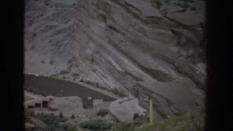 A 1959 Colorado view holds on cliff dwellings against banded sandstone, partially divided by a dark foreground bar.