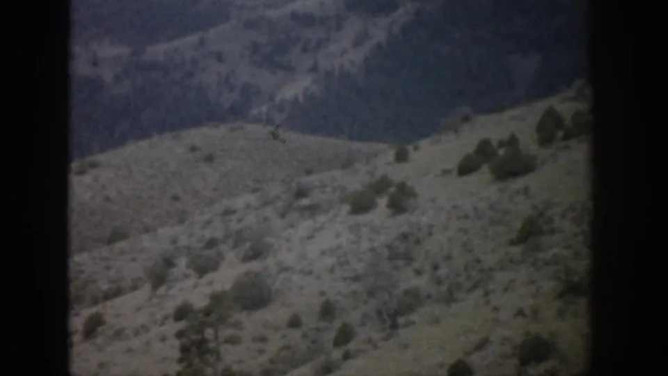 1959 Colorado home-movie frame showing arid rolling hills, sparse vegetation, and distant ridges with visible 8mm frame edges.